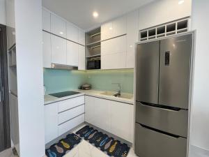 a kitchen with white cabinets and a stainless steel refrigerator at VINHOMES GRAND PARK Chillin Home 1BR Best View in Long Bình