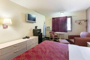 a hotel room with a bed and a couch and a chair at Americas Best Value Inn Beatrice in Beatrice