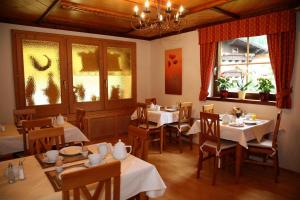 a restaurant with white tables and chairs and windows at Frühstückspension Friedheim in Filzmoos