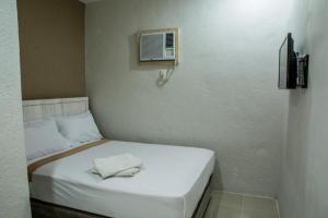 a small bedroom with a white bed with a air conditioner at Hotel Avenija in Olongapo
