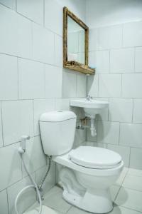 a white bathroom with a toilet and a sink at Hotel Avenija in Olongapo