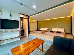 two beds in a room with a tv and a couch at The State Resort in Ban Wat Phrik
