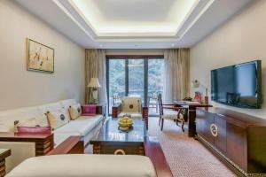a living room with a couch and a tv at Wudangshan Jianguo Hotel in Liuliping