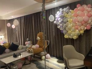 a teddy bear sitting in a chair in a room with balloons at Zhonghao Boutique Hotel Dalang Business Center in Tiantangwei