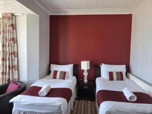 a hotel room with two beds and a red wall at The Cambrian in New Quay