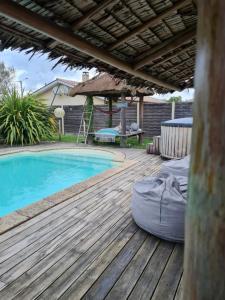 a wooden deck with a swimming pool and a pergola at La Villa du Teich in Le Teich