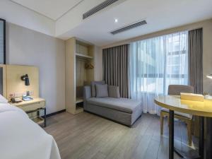 a hotel room with a bed and a chair and a table at Echarm Hotel Beihai Railway Station in Dianbailiao +231 photos