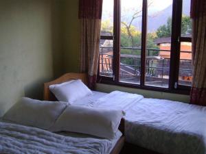 two beds in a bedroom with a view of a balcony at Mystique Highland Resort in Pokhara
