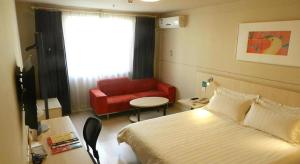 a hotel room with a bed and a red couch at Jinjiang Inn Pingyao Branch in Pingyao