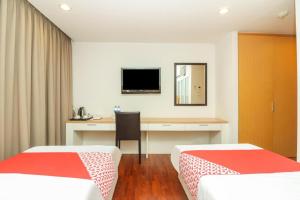a room with two beds and a desk with a television at OYO 225 Premier Place Bangkok in Bangkok