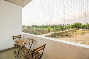 two chairs and a table on a balcony with a large window at Hotel O D' Jade in Hyderabad