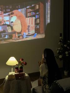 eine Frau sitzt mit einem Teddybär vor einem Tisch in der Unterkunft BB Homestay in Thôn Trường Giang