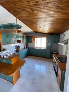 a large kitchen with green cabinets and a wooden ceiling at Hotel Gjika in Sarandë