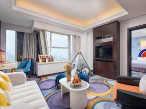 a living room with a white couch and a room with a bed at Yiwu Yimei Plaza Hotel in Yiwu