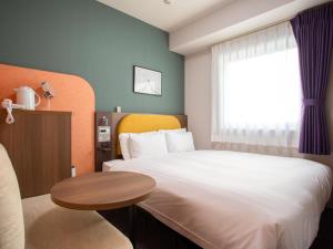 Un dormitorio con una cama y una mesa y una ventana. en Comfort Hotel ERA Tokyo Higashi Kanda, en Tokio