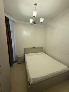 a small bedroom with a white bed and a chandelier at Sweet Batumi GEO in Itʼkhvisi