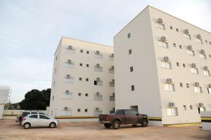 un gran edificio blanco con coches estacionados frente a él en Rota Hoteis Itumbiara, en Itumbiara