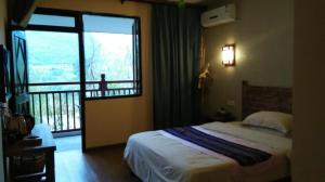a bedroom with a bed and a window with a balcony at Guilin Lotus Hotel in Guilin