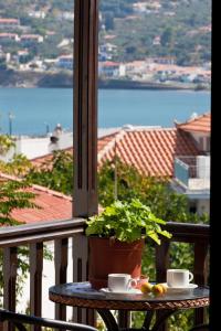 een tafel met een plant en twee kopjes op een balkon bij Sofia's Garden Studios in Skopelos Town