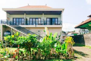 a house with a balcony and plants in front of it at Anantalla Homestay in Sidemen