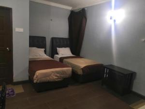 a hotel room with two beds and a table at OYO 90473 Opah Inn Hotel in Jertih