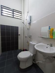 a bathroom with a white toilet and a sink at OYO Homes 90606 Casaria Cherating in Cherating