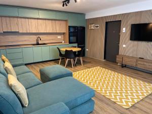a living room with a blue couch and a kitchen at Apartament Tei in Gura Humorului