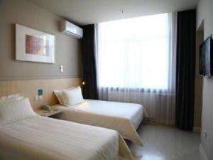 une chambre d'hôtel avec deux lits et une fenêtre dans l'établissement Jinjiang Inn Yichun Water Park Branch, à Shuangzihe