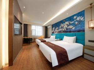 a hotel room with two beds and a painting on the wall at Magnotel Business Yangzhou China Grand Canal Museum Wanda Plaza in Yangzhou +247 photos