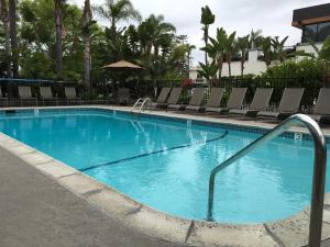 a large blue swimming pool with chairs in a resort at La Avenida Inn in San Diego