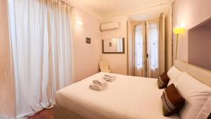 une chambre blanche avec deux lits et une fenêtre dans l'établissement Dimora Storica, à Milan