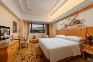 a hotel room with a large bed and a desk at Vienna International Hotel Guangzhou Jichang Road Huangshi in Guangzhou