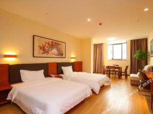 une chambre d'hôtel avec deux lits et une table dans l'établissement 7 Days Premium·Guanyun Nanjing West Road Hesheng Plaza, à Guanyun