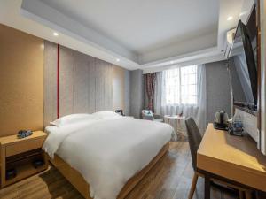 a hotel room with a large white bed and a desk at Yimi Hotel Guangzhou Yuexiu Park North Branch in Guangzhou