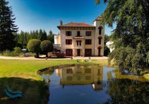 a large house with a pond in front of it at Domaine de Marchal - Le balcon du Parc - tente éco-lodge in Celles-sur-Durolle