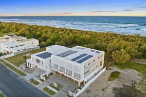 Baja on Cylinders - Beachfront Bliss في كينغسكليف: اطلالة جوية على مبنى ابيض بجانب المحيط