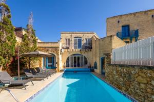 a swimming pool with lounge chairs and a house at Dionisia Holiday Home in Għasri