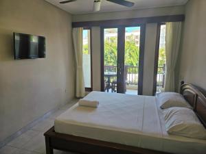 sypialnia z łóżkiem, telewizorem i balkonem w obiekcie Keke Homestay Sanur w mieście Sanur