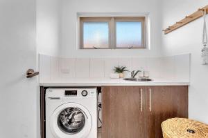 a kitchen with a washing machine and a sink at Christies Grove - Seaside Bliss near McLaren Vale in Christies Beach