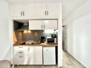 a kitchen with white cabinets and a microwave at Estudio con Encanto, Piscina, BBQ y Terraza para una Estancia Ideal in Costa Del Silencio