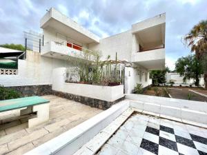 a white house with a patio with a bench at Estudio con Encanto, Piscina, BBQ y Terraza para una Estancia Ideal in Costa Del Silencio