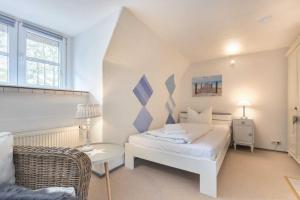 a white bedroom with a bed and a chair at Ferienhaus Seeraeuberhaeuschen ID 442 in Tating
