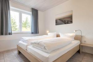 a bedroom with two beds with white sheets and a window at Rechte Haushaelfte ID 905 in Sankt Peter-Ording