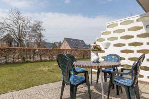 - une table avec des chaises et un vase de fleurs sur la terrasse dans l'établissement Linke Haushaelfte ID 906, à Sankt Peter-Ording