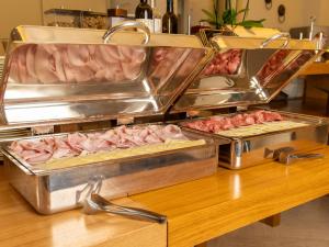 a counter with three trays of ham and meat at Hotel Cristallo in Giulianova