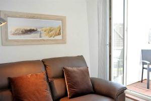 a brown leather couch sitting in a living room at Wohnung 3 ID 181 in Sankt Peter-Ording +13 photos