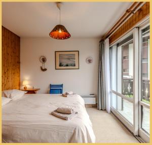a bedroom with a bed and a large window at Le Chamois d'Or I T4 I Les Gets in Les Gets