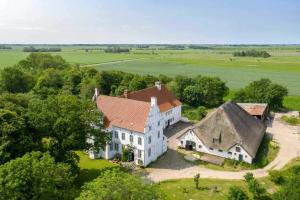 une vue aérienne d'une grande maison blanche avec un toit rouge dans l'établissement Wohnung 4 Anna Owena ID 386, à Oldenswort 20 autres photos