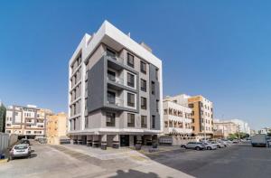a tall white building with cars parked in a parking lot at SADEN Al-Salama in Jeddah