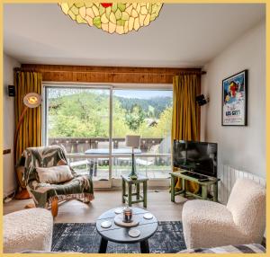 a living room with a tv and a large window at Le Chamois d'Or I T4 I Les Gets in Les Gets